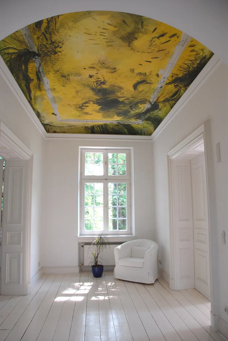 Heller, leerer Altbau-Raum mit bemalter Decke und hohem Fenster